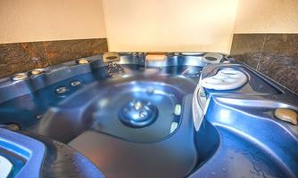 A blue whirlpool with water and various massage jets. The room has a calm atmosphere and elegant walls.
