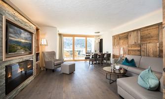 An elegant living room with modern design and wooden elements. Large windows provide a beautiful view of the landscape.