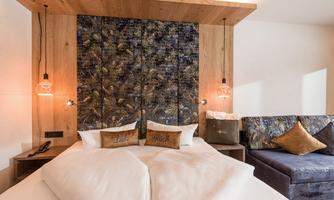 A modern room with a comfortable double bed and stylish wood and fabric accents. The cozy corner with a sofa invites you to relax.
