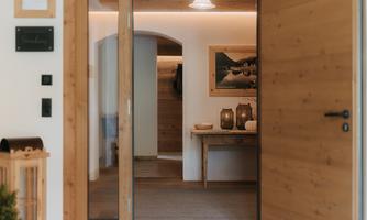 An inviting hallway with wooden doors and soft lighting. Decorative lanterns are on a table, and there is a picture on the wall.