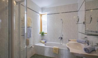 A modern bathroom with a bathtub and a separate shower.  
Bright tiles and soft colors create an inviting atmosphere.