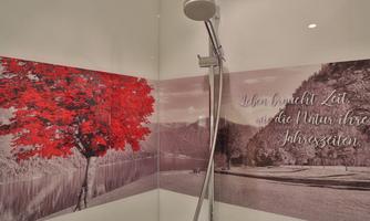 A stylish shower ambiance with a red tree on a black-and-white landscape. On the wall, the saying reads: “Love brings time, like nature brings its seasons.”