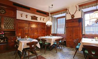 A cozy restaurant with wooden paneling and rustic decor. The tables are elegantly set and the walls are decorated with hunting trophies.