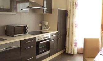 A modern kitchen with stylish furniture and appliances. The room is bright with a window that lets in daylight.