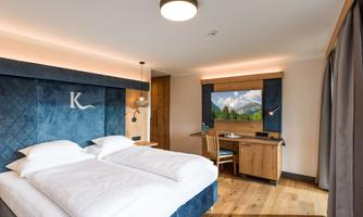 A modern hotel room with two twin beds and a large window. The decor is stylish and cozy, perfect for a relaxing stay.