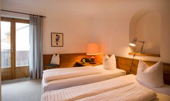 A cozy bedroom with two single beds and a warm atmosphere. The windows let in plenty of daylight and offer a view outside.