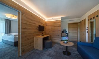 A modern room with wooden walls and a cozy sofa. There is a small table and a television, creating an inviting atmosphere.