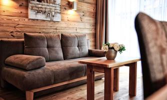 A cozy living room with a gray sofa and a wooden table. On the table is a vase with white roses.