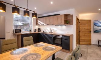 A modern kitchen with wooden shelves and elegant appliances. The dining area features a large table and comfortable chairs.