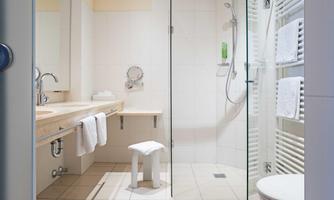 A modern bathroom with a shower and a sink. Towels are neatly hanging on a towel rack.