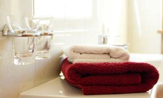 A well-designed bathroom with a stack of folded red and white towels. Next to it are two glasses on a countertop.