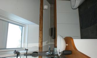 A modern bathroom with a shower, toilet, and sink, featuring a large roof window. The decor is minimalist, with wooden and white elements.