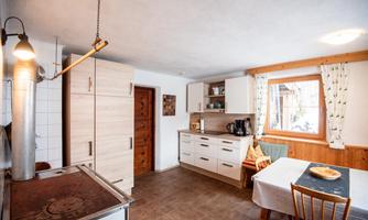 A modern kitchen with bright wooden furniture and plenty of space. A table with chairs and a small breakfast arrangement creates an inviting atmosphere.