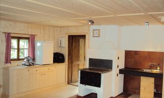 A cozy kitchen with wooden decor, a stove, and a refrigerator. The large windows provide plenty of light.