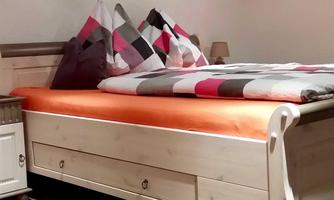 A cozy bedroom with a bright bed and colorful pillows. Pictures hang on the wall, completing the ambiance.