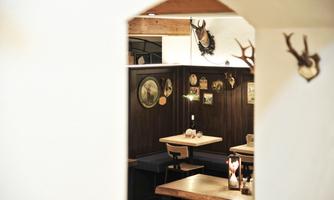 A cozy restaurant with wooden tables and a warm atmosphere. Decorative pictures and antlers hang on the walls.