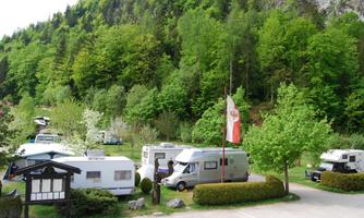 A quiet campsite nestled among green trees. Several RVs are surrounded by a picturesque landscape.