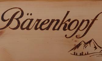 A wooden sign with the inscription "Bear Head" and a simple mountain drawing. The sign conveys a nature-friendly atmosphere.