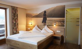 A modern room with a large bed and wooden furniture. On the wall, there is a picture of a person in front of a landscape.