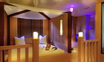 A stylish wellness room with a comfortable bed, gentle lighting, and a relaxing atmosphere. The wooden paneling and soft cushions create an inviting retreat.