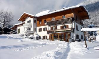 A charming house in winter, surrounded by snow. The sky is clear and the landscape looks peaceful.