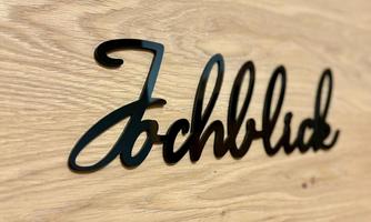 A stylish inscription with the word "Fachblick" on a wood-paneled surface. The lettering is elegant and modern.