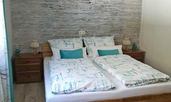 A cozy bedroom with a double bed and modern wooden dressers. The walls are painted in soft colors, and the floor is decorated with a colorful rug.