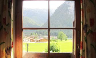 A window view of a picturesque landscape with mountains and meadows. The curtains are colorful and give the room a cozy atmosphere.