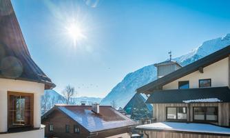 A clear blue sky over a picturesque mountain village. The sunny roofs of the houses shine in the winter landscape.