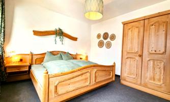 A cozy bedroom with a large wooden bed and simple furniture. Soft colors and warm light create an inviting atmosphere.
