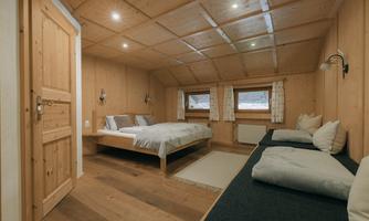 A cozy room with wooden walls and a large bed. There is a window with curtains and a comfortable seating area.
