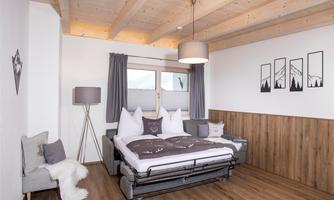 A modern bedroom with wooden ceilings and a cozy bed. The walls are in soft colors, and there are stylish decorations.