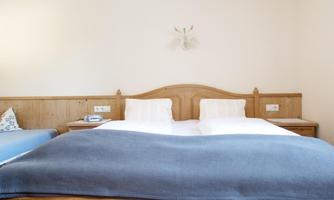 A cozy bedroom with a large double bed and soft pillows. The wooden furniture gives the room a warm atmosphere.