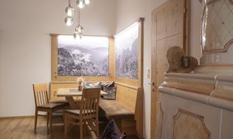 A cozy dining area with wooden-paneled walls and a large window view of mountain landscapes. The room is brightly lit and furnished with stylish furniture.