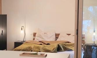 A modern bedroom with a cozy bed and soft colors. The lighting creates an inviting atmosphere.