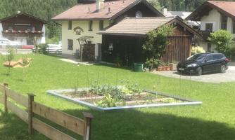 A charming house with a well-maintained garden and a small vegetable garden. The surroundings are green and quiet, surrounded by mountains.