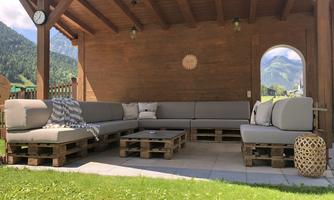 A cozy lounge corner made of pallets with gray cushions. In the background, green mountains and a clear sky can be seen.