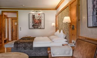 A cozy room with a large bed and wooden furniture. It includes a comfortable armchair and a relaxing atmosphere.