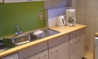 A modern kitchen with bright cabinets and a green wall. On the countertop, there is a coffee machine and a kettle.