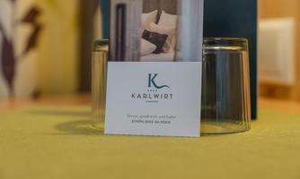 A table decoration with a "Karlwirt" logo and glasses in the background. The table is covered with a green tablecloth.