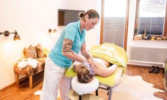 A massage session in a cozy room. A therapist is taking care of a relaxed client on the table.