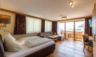 A spacious bedroom with a double bed and a cozy seating area. Large windows offer a beautiful view and plenty of natural light.