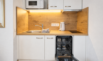 A modern kitchen unit with a sink, dishwasher, and microwave. The wood look gives the kitchen a warm atmosphere.