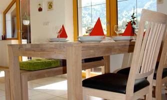 A bright dining area with a wooden table and modern design. The table features decorative red tablecloths and a beautiful view of the mountains.