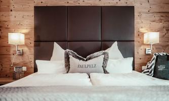 A cozy bedroom with a large bed and wooden paneling. Two nightstands with lamps and pillows create an inviting atmosphere.