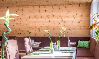 An inviting restaurant with wooden-paneled walls and cozy tables. There are decorative plants and a bright, friendly atmosphere.