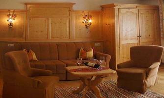 A cozy living room with a beige couch and two armchairs. The warm wood tones and simple decor create an inviting atmosphere.