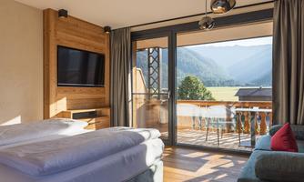 A modern hotel room with large windows and a beautiful view of the mountain landscape. The room is bright and comfortably furnished.