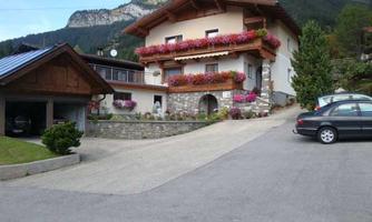 A cozy house with flower boxes and a traditional alpine style.  
Surrounded by mountains and a quiet street.