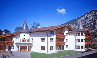 A modern building with a distinctive design and turret. It is located in a mountain landscape with a clear blue sky.